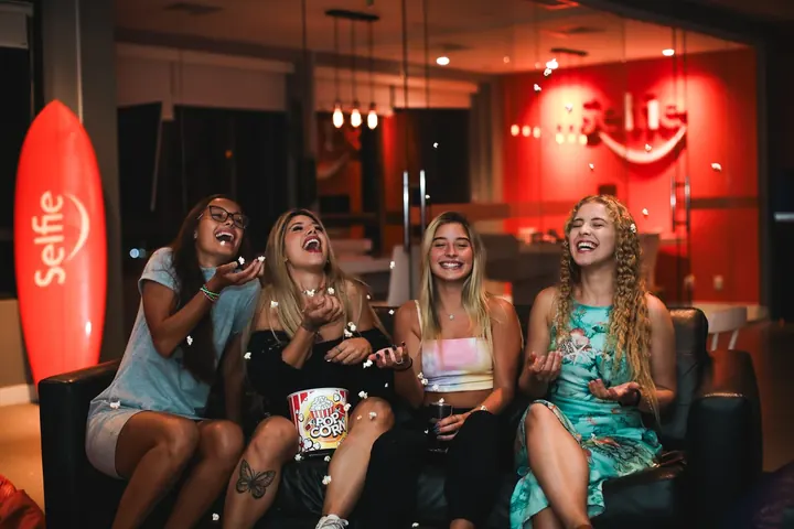 Friends laughing under a Selfie neon sign