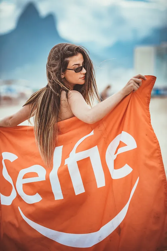 Woman wrapped in an orange Selfie beach towel in Rio de Janeiro